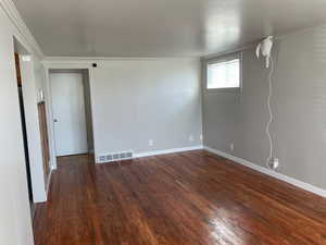Unfurnished room with dark wood-style flooring and ornamental molding