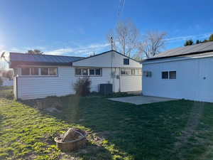 Back of house featuring a patio, a lawn, a fire pit, and a metal roof