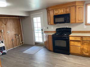 Kitchen featuring black appliances, light countertops, and wood finish cabinetry