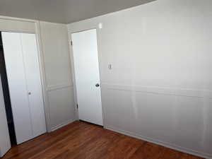 Unfurnished bedroom featuring dark wood finished floors and a closet
