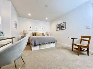Bedroom with light colored carpet, a textured ceiling, recessed lighting, and a textured wall