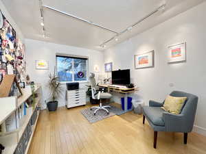 Office space featuring rail lighting, a textured ceiling, and light wood-style floors