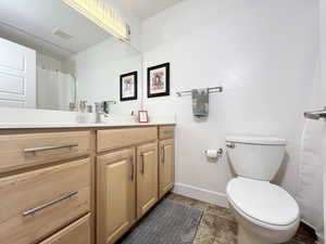 Full bath with vanity, curtained shower, and dark stone finish floors