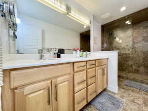 Full bath with double vanity, walk in shower, a textured ceiling, and recessed lighting