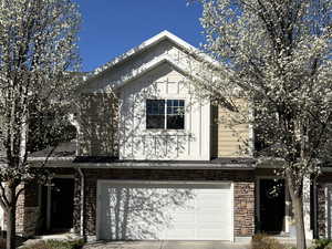 View of front of home with stone siding, an attached garage, and concrete driveway