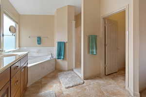 Bathroom with a garden tub, vanity, a stall shower, and light tile patterned floors