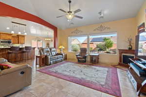 Living area with ceiling fan, a fireplace, suspended lighting, lofted ceiling, and light tile patterned floors