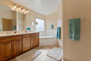 Bathroom with double vanity, a bath, and light tile patterned floors