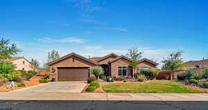 Single story home with stone siding, stucco siding, an attached garage, and driveway