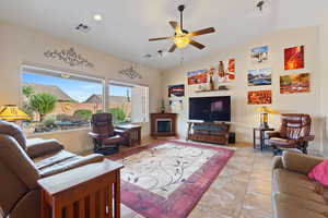 Living area with ceiling fan, tile patterned floors, lofted ceiling, and a glass covered fireplace