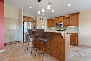 Kitchen featuring wood finish cabinetry, stainless steel appliances, a kitchen breakfast bar, tasteful backsplash, and lofted ceiling
