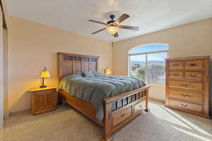 Bedroom featuring light colored carpet, ceiling fan, and a mountain view
