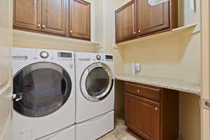 Laundry area featuring washing machine and clothes dryer, cabinet space, and light tile patterned floors