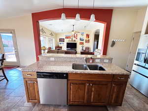 Kitchen featuring ceiling fan, stainless steel appliances, open floor plan, arched walkways, and light stone counters