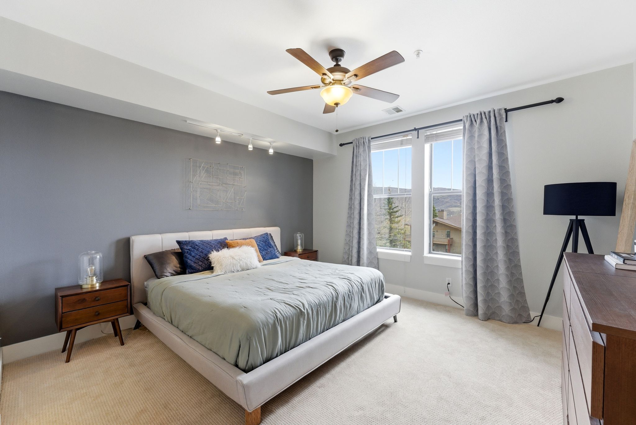 Bedroom with light carpet, a ceiling fan, and rail lighting
