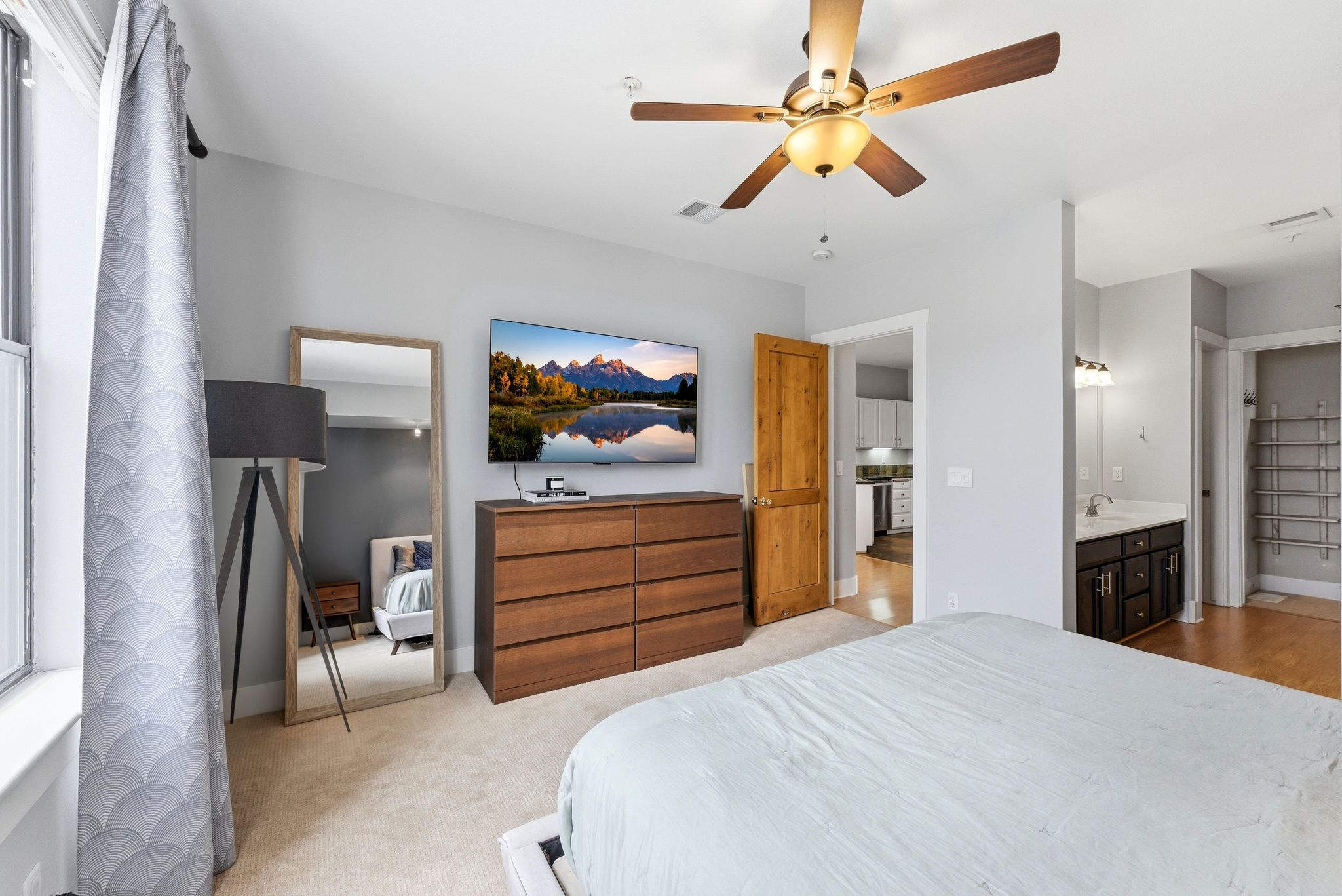Bedroom featuring ceiling fan, ensuite bath, and light colored carpet