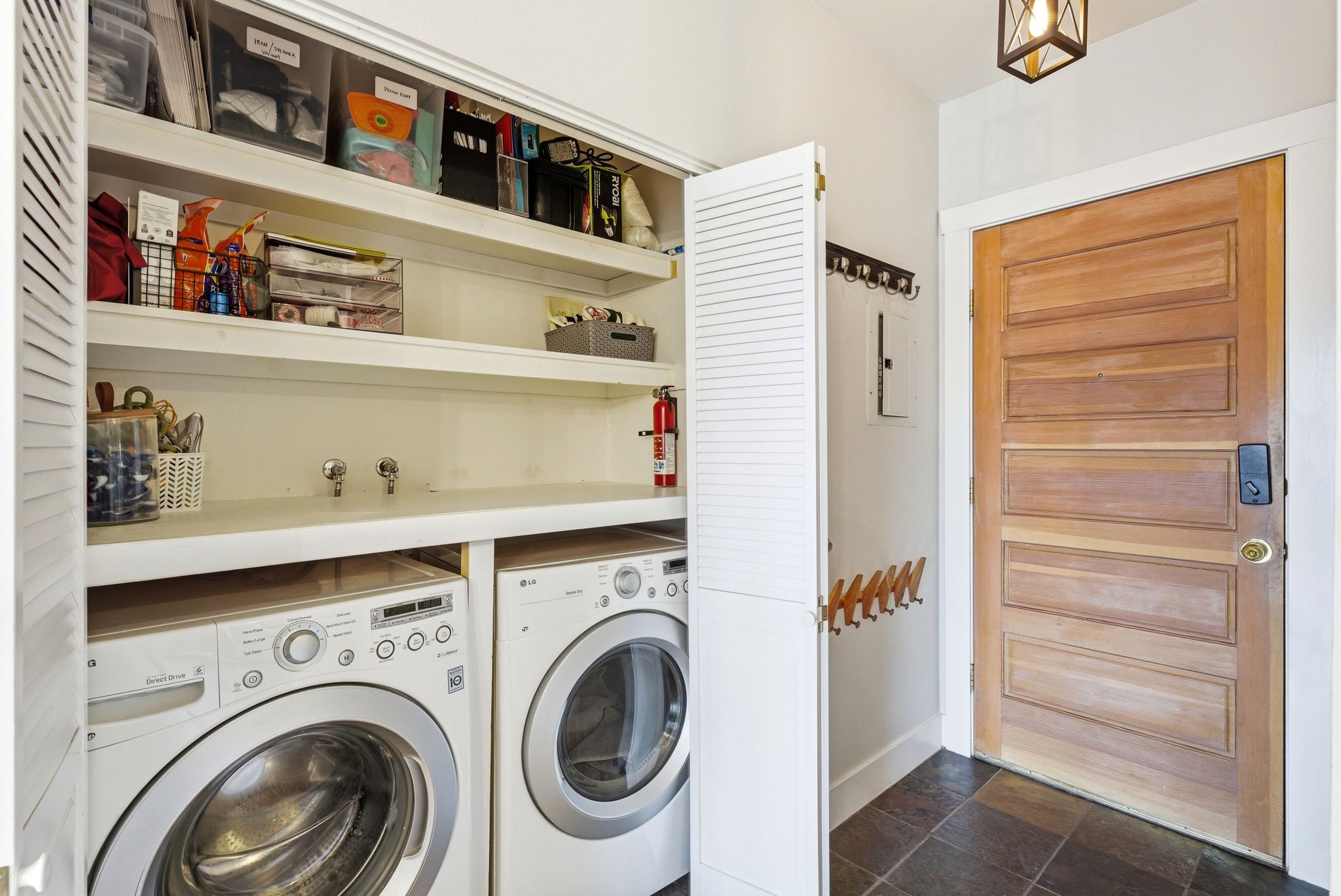 Laundry area with independent washer and dryer, dark stone finish floors, and electric panel