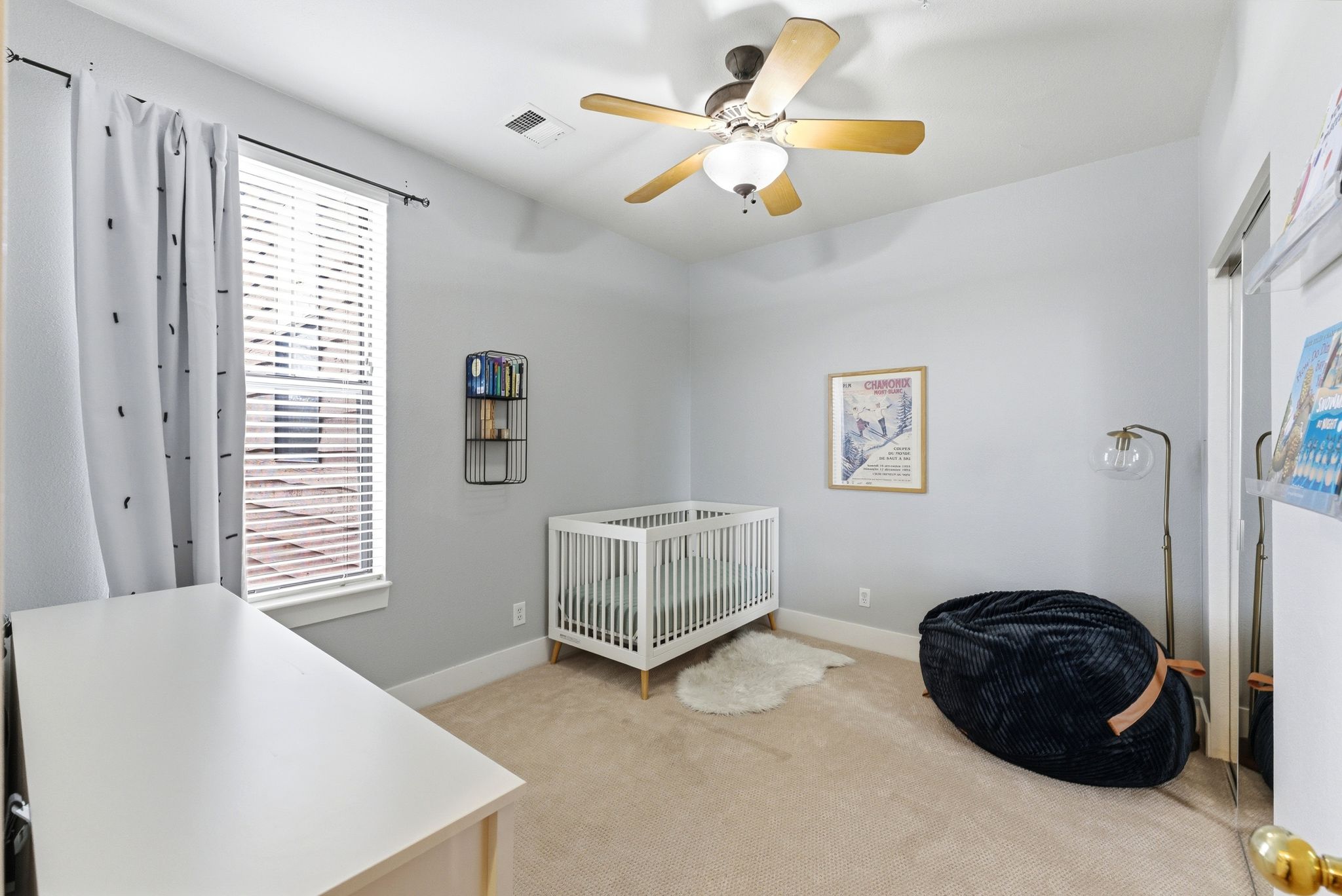 Bedroom with light carpet, a nursery area, and ceiling fan