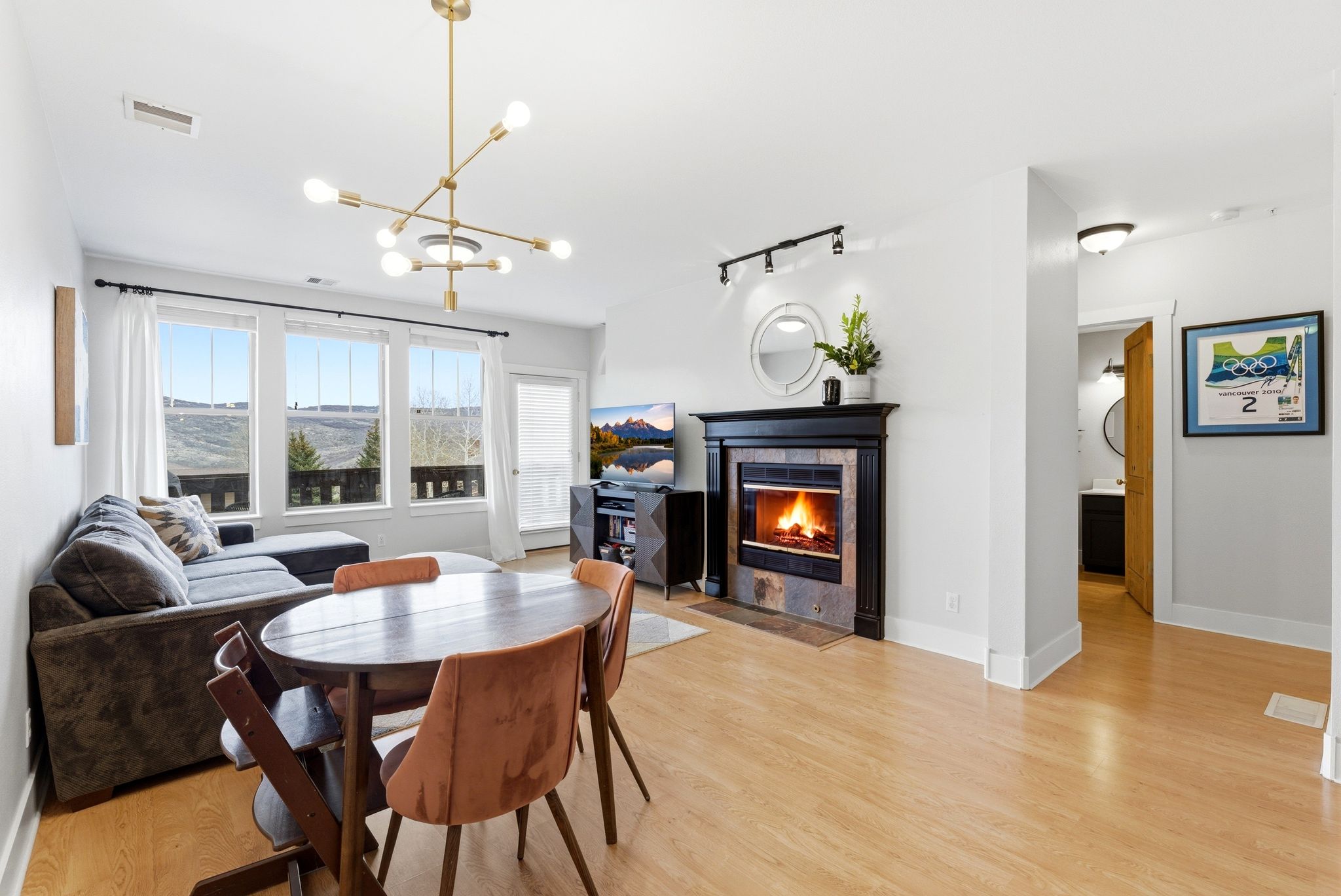 Dining space with a tiled fireplace, hanging lights, and light wood-style flooring