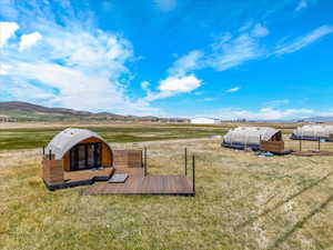 View of green lawn with a view of rural / pastoral area, a deck with mountain view, and an outbuilding