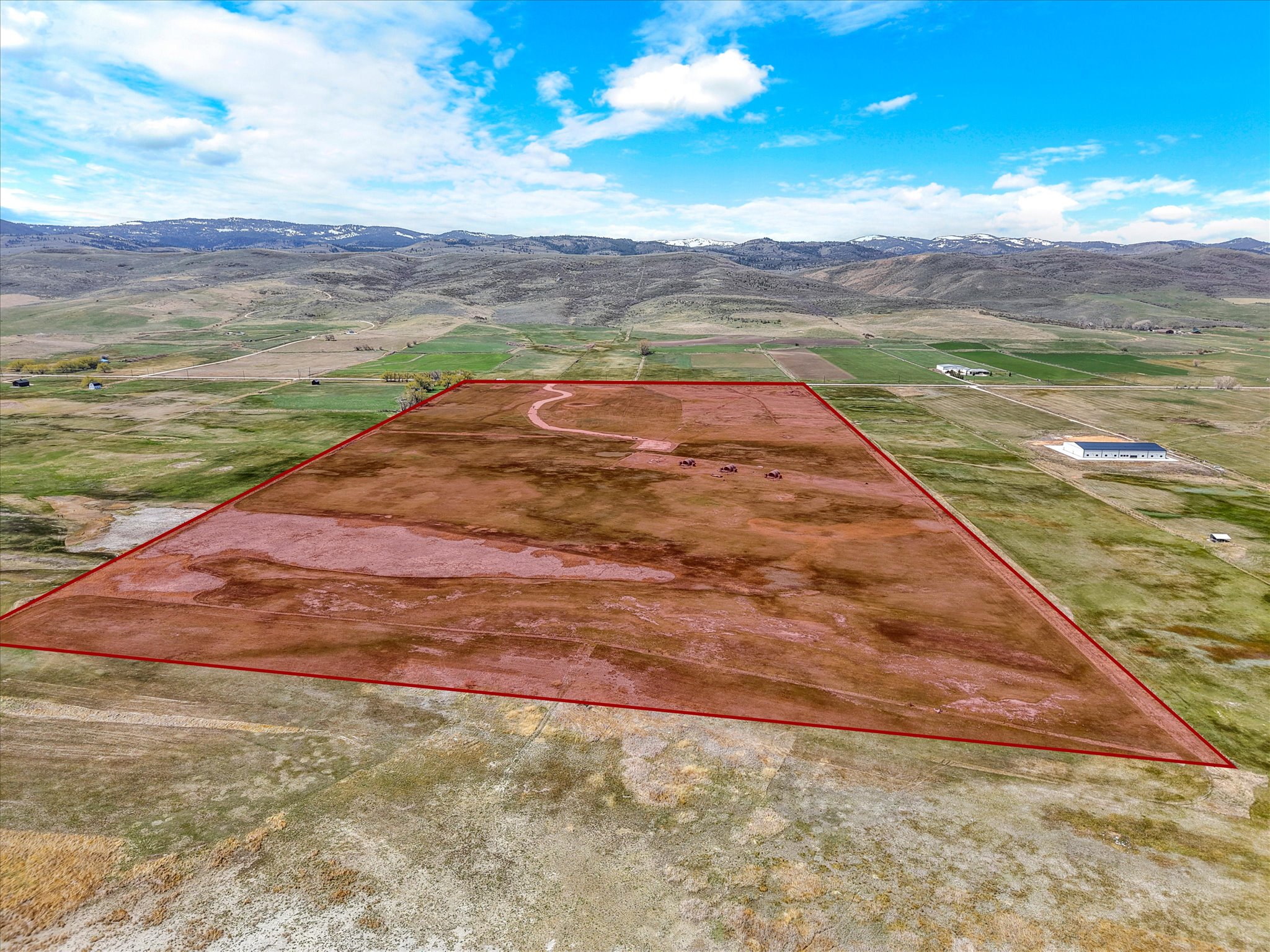 Aerial view of sparsely populated area featuring a mountain backdrop and property parcel outlined