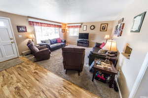 Living room featuring wood finished floors, a baseboard heating unit, and a textured ceiling