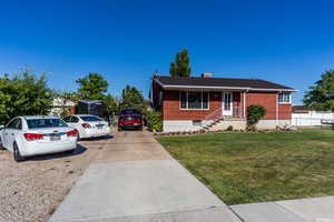 View of front of home featuring brick siding, covered porch, concrete driveway, and a chimney