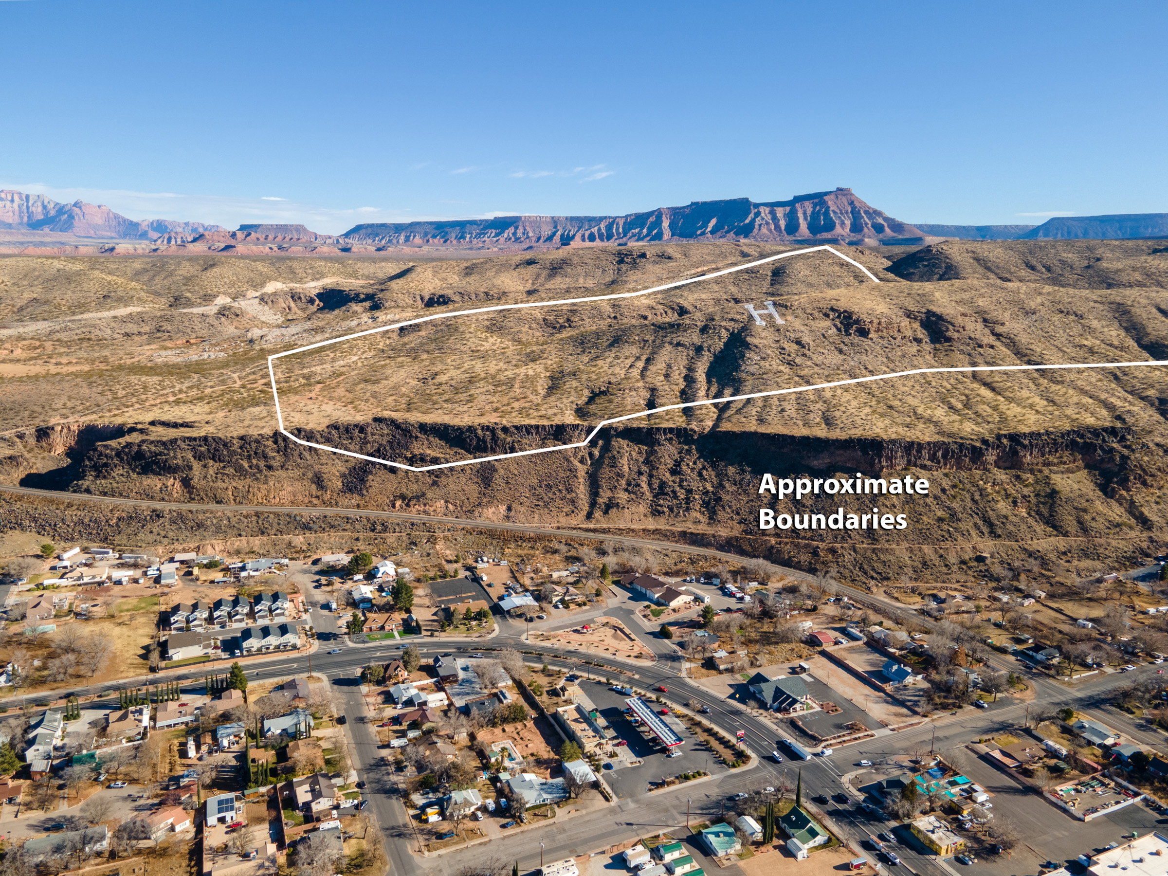 Aerial perspective of suburban area with a mountain backdrop and property parcel outlined