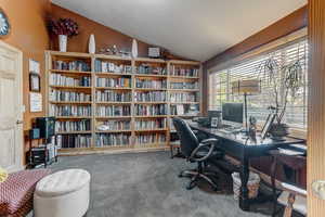 Home office with lofted ceiling and carpet flooring