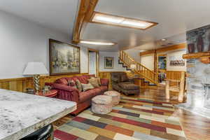 Living area with wood finished floors, wainscoting, wood walls, and a stone fireplace