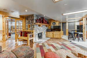 Living room featuring wooden walls, a stone fireplace, light wood-style flooring, and recessed lighting