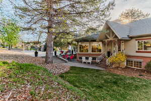 View of home's exterior featuring a patio area, a chimney, brick siding, a yard, and stucco siding