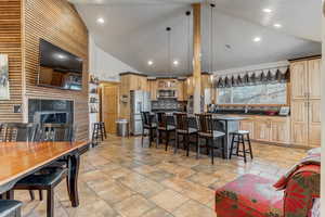 Two tone kitchen with a breakfast bar, vaulted ceiling, stainless steel appliances, a center island, and pendant lighting