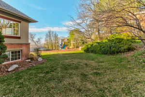 View of grassy yard featuring a playground