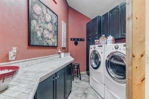 Laundry room featuring cabinet space, a textured wall, and separate washer and dryer