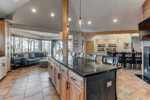 Kitchen with open floor plan, a center island, a breakfast bar, dark stone countertops, and decorative light fixtures