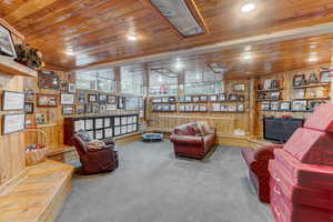 Carpeted living room featuring wood ceiling, wooden walls, and recessed lighting