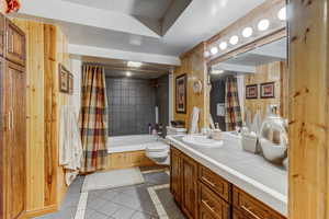Full bathroom featuring vanity, shower / tub combo, wood walls, and light tile patterned flooring