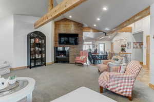 Living area with light carpet, a warm lit fireplace, recessed lighting, and vaulted ceiling
