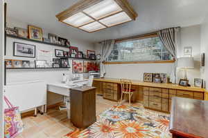 Office with built in desk and light tile patterned floors