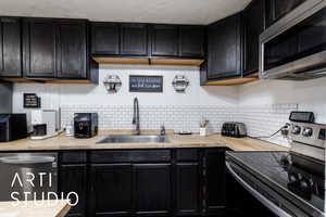 Kitchen with dark cabinets, stainless steel appliances, and butcher block countertops