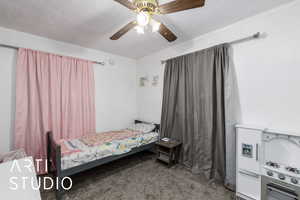 Bedroom featuring dark carpet, a textured ceiling, and a ceiling fan