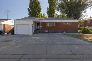 Single story home featuring driveway, a garage, and brick siding