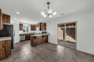 Kitchen featuring a peninsula, dark tile patterned floors, suspended lighting, and stainless steel appliances