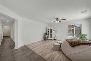 Living room with wood finished floors, a textured ceiling, and ceiling fan