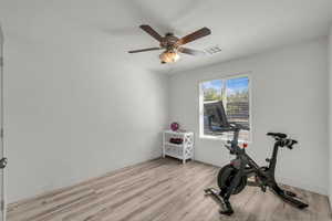 Exercise room with light wood-style flooring and ceiling fan