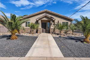 View of front of property featuring a tiled roof, stucco siding, and stone siding