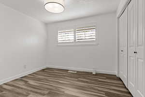 Unfurnished bedroom featuring dark wood-style flooring, a closet, and a textured ceiling