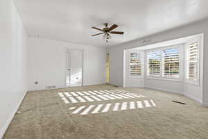 Empty room featuring a ceiling fan and light colored carpet