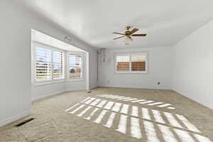Carpeted empty room featuring baseboards and a ceiling fan